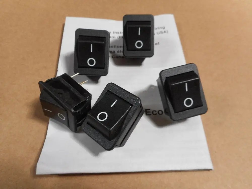Fünf schwarze Hauptschalter mit I/O-Symbolen, auf einem Untergrund liegend, gemeinsam dargestellt. Remeha ist als Marke erkennbar.